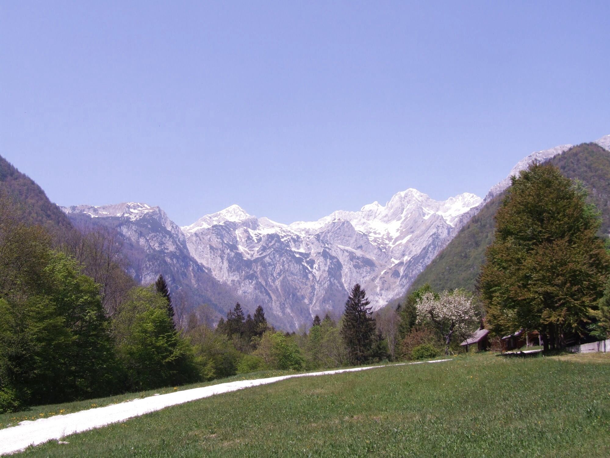 Pogled na zasnežene vrhove Kamniško-Savinjskih Alp in zeleno dolino
